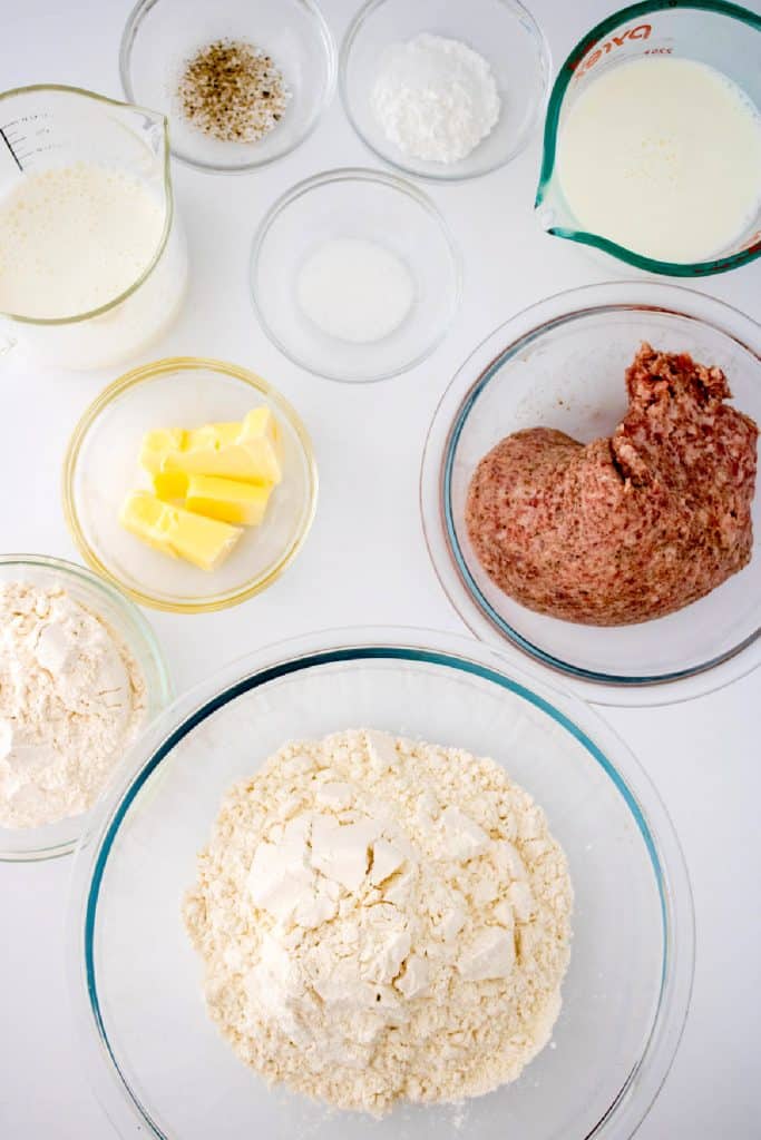 flour, baking powder, salt, milk butter, sausage on white surface.