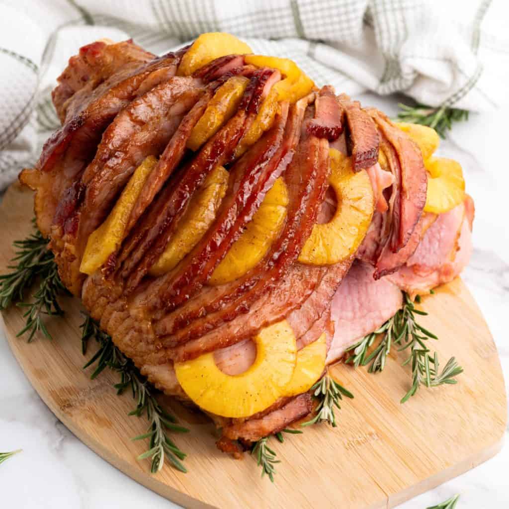 Brown sugar glazed pineapple ham on cutting board.