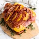 Brown sugar glazed pineapple ham on cutting board.