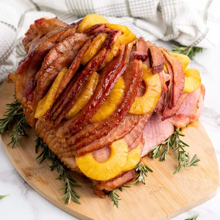 Brown sugar glazed pineapple ham on cutting board.