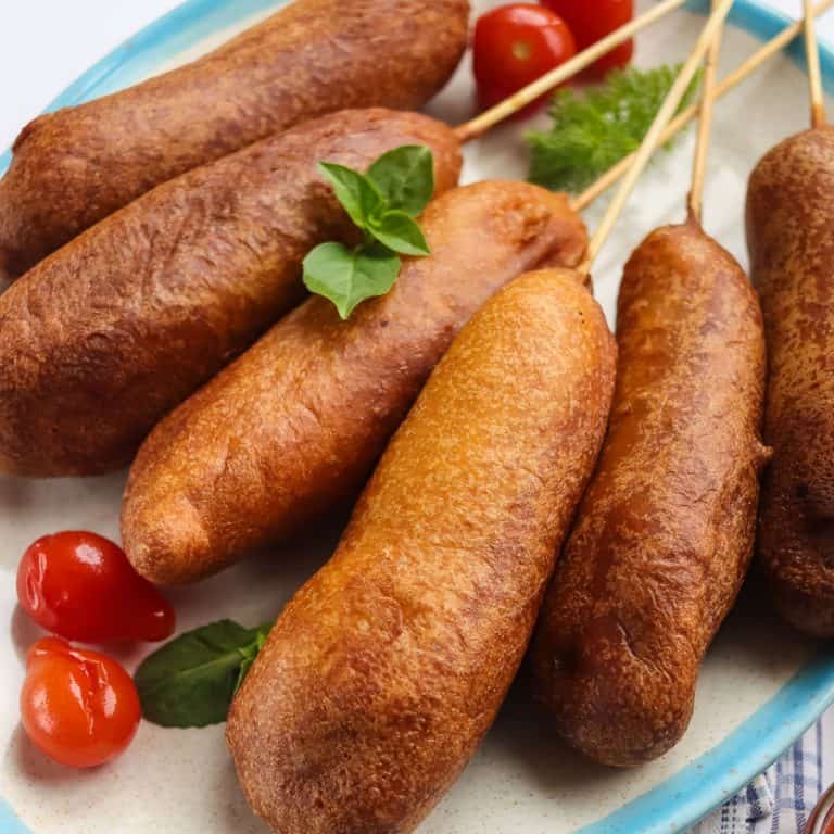 Stck of corn dogs on plate.