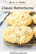 A close-up of classic butterhorn pastries on a cooling rack, topped with white icing and almond slices. Text above reads “How to Make Classic Butterhorns,” and below is thebuttercookie.com.