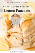 A stack of fluffy lemon pancakes topped with butter, syrup, and lemon slices, with a fork pressed into the stack. Text on the image reads: “Citrus Lovers Breakfast Lemon Pancakes.”.